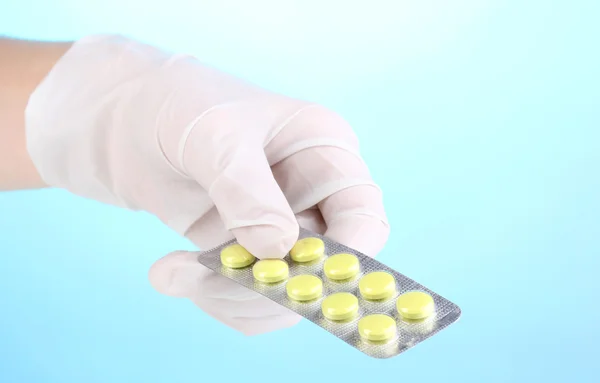 Tabletten in der Hand auf blauem Hintergrund — Stockfoto
