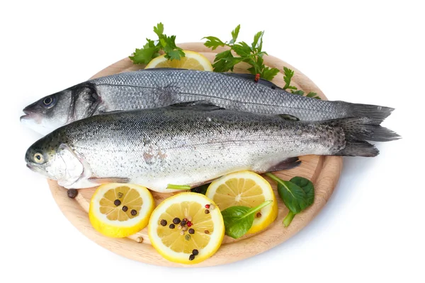 Pesci freschi con limone, prezzemolo e spezie su tagliere di legno isolato su bianco — Foto Stock