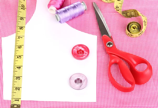 Scissors, threads, buttons, measuring tape and pattern on fabric close-up — Stock Photo, Image