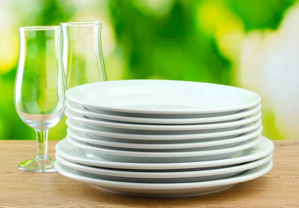 Piatti puliti su tavolo di legno su sfondo verde — Foto Stock