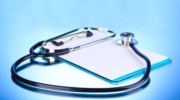 Medical stethoscope and clipboard on blue background — Stock Photo, Image