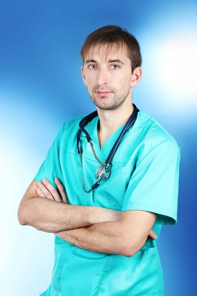 Mężczyzna młody lekarz z stetoskop na niebieskim tle — Zdjęcie stockowe