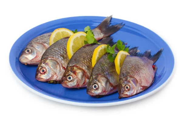 Peces frescos con limón y perejil en plato aislado sobre blanco —  Fotos de Stock