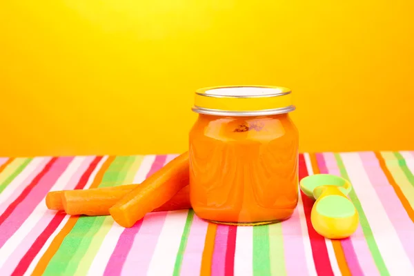 黄色の背景にナプキンにスプーンで赤ちゃんのピューレの jar ファイル — ストック写真