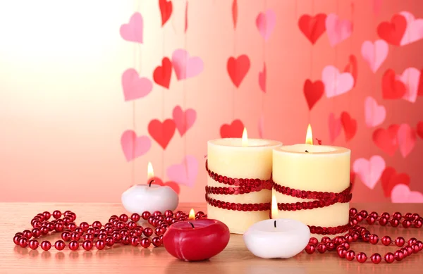Beautiful candles with romantic decor on a wooden table on a red background Stock Picture
