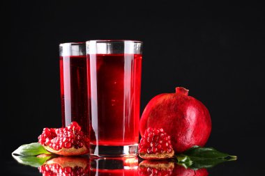 Ripe pomergranate and glasses of juice on black background clipart