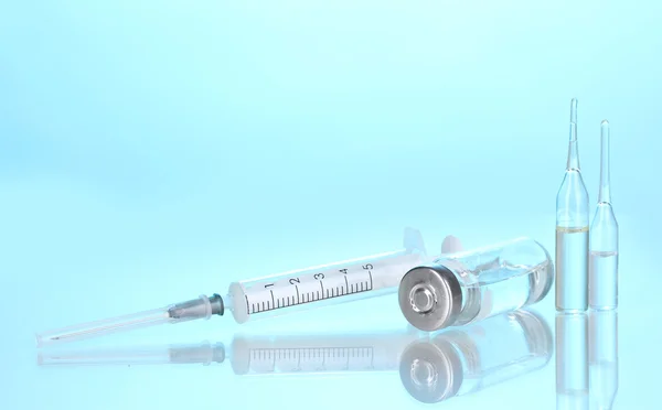 Spritze und medizinische Ampullen auf blauem Hintergrund — Stockfoto
