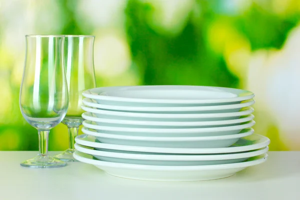 Clean dishes on table on green background