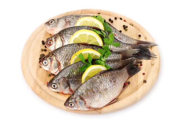 Fresh fishes with lemon, parsley and spice on wooden cutting board isolated on white — Stock Photo, Image