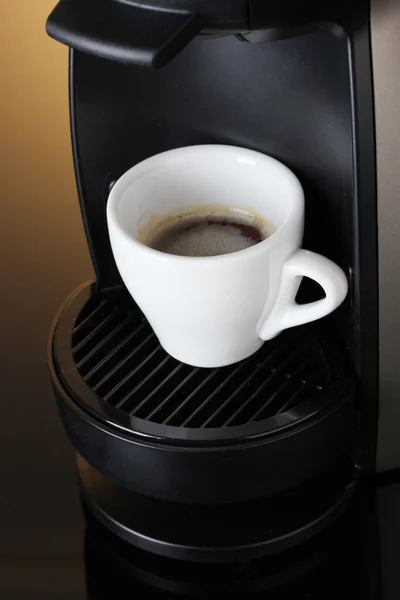 Эспрессо машина и чашка кофе на коричневом фоне — стоковое фото