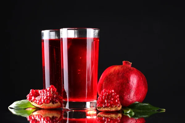 Ripe pomergranate and glasses of juice on black background — Stock Photo, Image