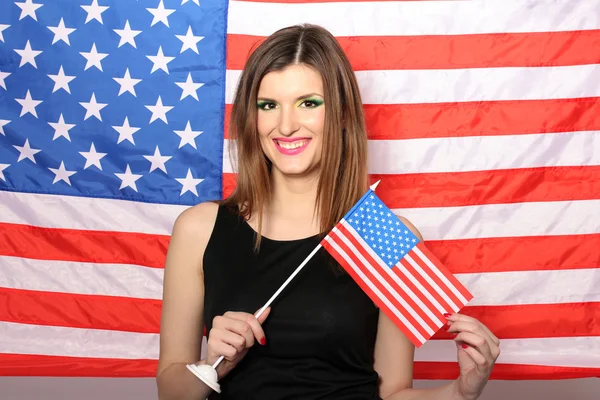 Beautiful young woman with the American flag on the background — Stock Photo, Image