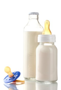 Bottles of milk and soother isolated on white