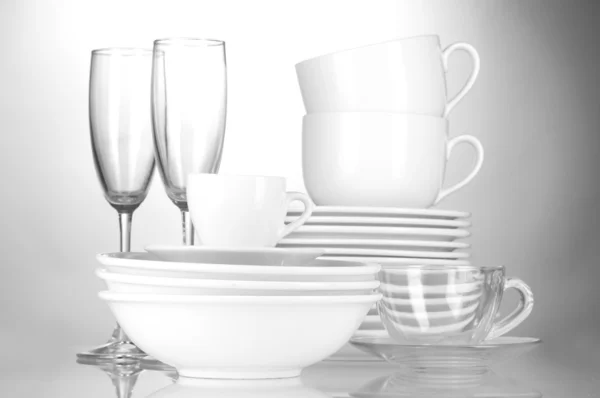 Tigelas vazias, pratos, copos e copos sobre fundo cinza — Fotografia de Stock