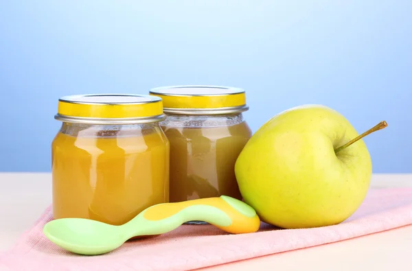 Jars of baby puree with spoon on napkin on blue background — Stock Photo, Image