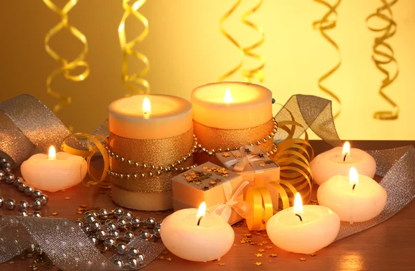 Schöne Kerzen, Geschenke und Dekor auf Holztisch auf gelbem Hintergrund — Stockfoto