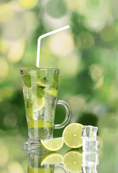 Glass of cocktail with lime and mint on green background — Stock Photo, Image