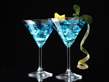 Blue cocktail in martini glasses on black background clipart