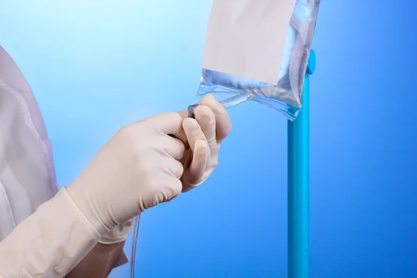 Enfermeira fazendo infusão em fundo azul — Fotografia de Stock