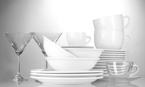Üres tálak, tányérok, poharak és csészék szürke háttér — Stock Fotó