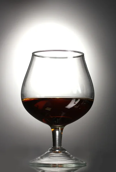 Glass of cognac on grey background — Stock Photo, Image
