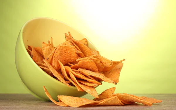 Вкусные картофельные чипсы в зеленой миске на деревянном столе на зеленом фоне — стоковое фото