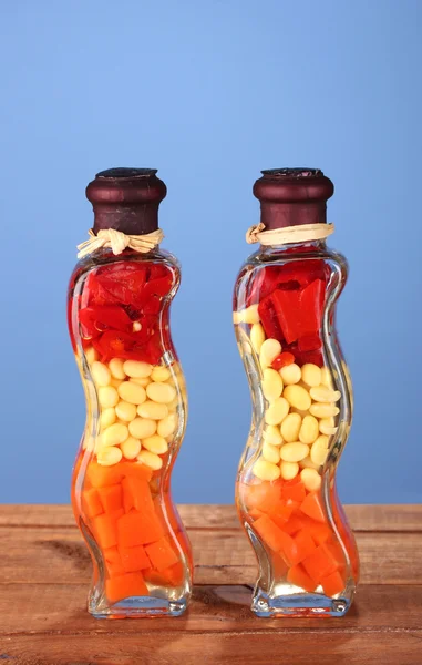 Két üveg, piros paprika, bab, sárgarépát, konyhai dekor kék háttér — Stock Fotó