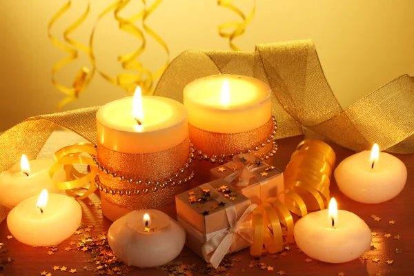 Krásné svíčky, dárky a výzdoba na dřevěný stůl na žlutém podkladu — Stock fotografie