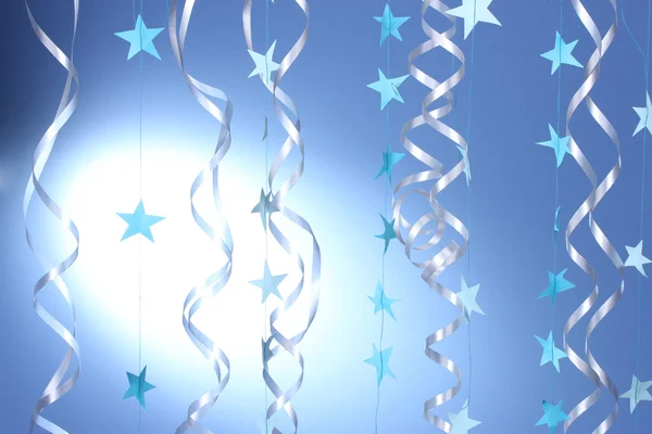 Schöne Luftschlangen und Sterne auf blauem Hintergrund — Stockfoto