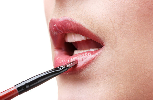 Beautiful woman applying lip gloss