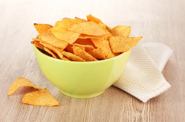 Tasty potato chips in green bowl on wooden table — Stock Photo, Image