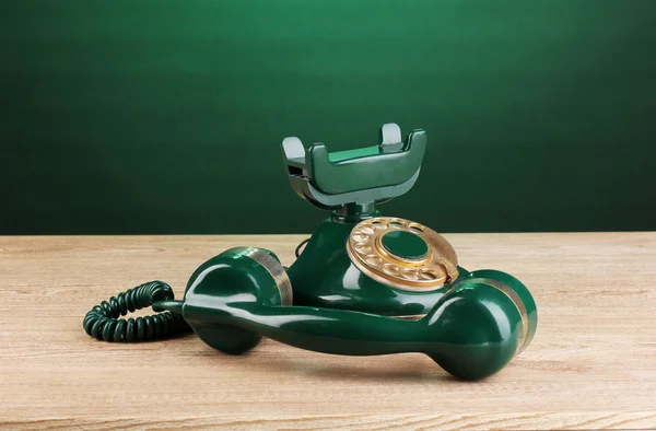Ретро телефон на деревянном столе на зеленом фоне — стоковое фото