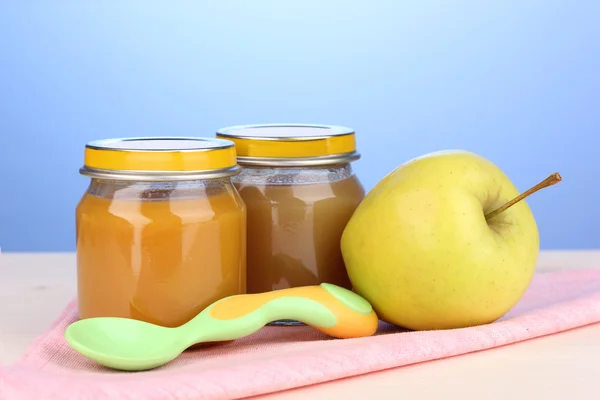 stock image Jars of baby puree with spoon on napkin on blue background