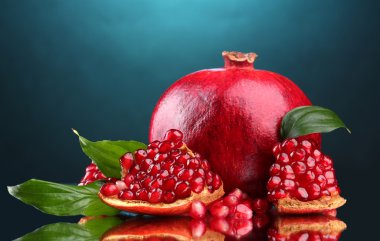 Ripe pomegranate fruit with leaves on blue background clipart