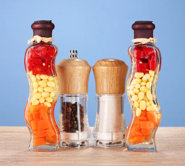 Iki şişe kırmızı biber, fasulye, havuç, tuz ve kagit üzerinde mavi arka plan ile mutfak dekorasyonu için — Stok fotoğraf