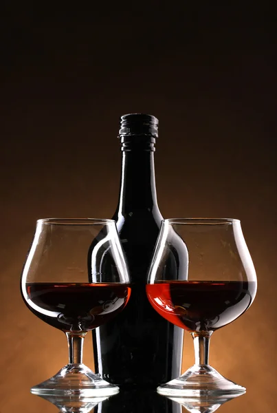 Óculos de conhaque e garrafa sobre fundo marrom — Fotografia de Stock