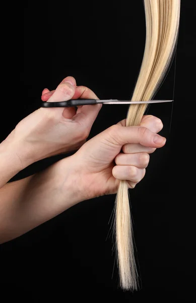 Lesklé světlé vlasy kadeřnictví rukou izolovaných na černém — Stock fotografie