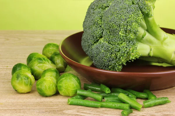Taze brokoli lahana ve Fransızca fasulye yakın çekim yeşil zemin üzerine ahşap masa ile plaka üzerinde — Stok fotoğraf