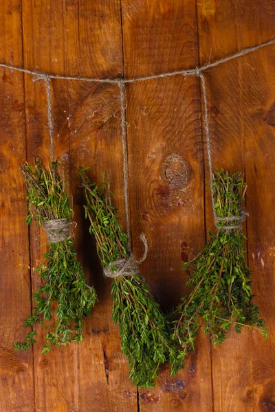 Tomillo verde fresco colgado en la cuerda sobre fondo de madera —  Fotos de Stock