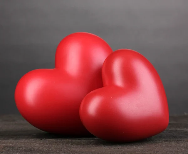 Dois corações vermelhos decorativos na mesa de madeira no fundo cinza — Fotografia de Stock