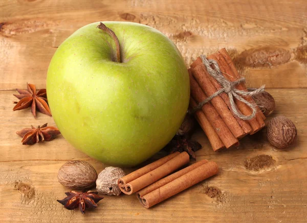 Tyčinky skořice, zelené jablko, muškátový oříšek a anýzu na dřevěný stůl — Stock fotografie
