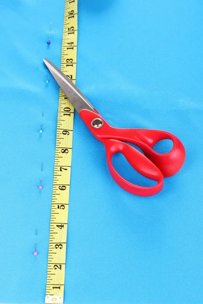 Scissors and measuring tape on blue fabric — Stock Photo, Image
