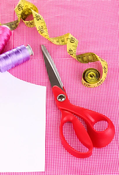 Tesoura, fios, fita métrica e padrão em close-up de tecido — Fotografia de Stock