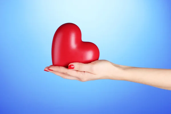 Rood hart in vrouw hand op blauwe achtergrond — Stockfoto