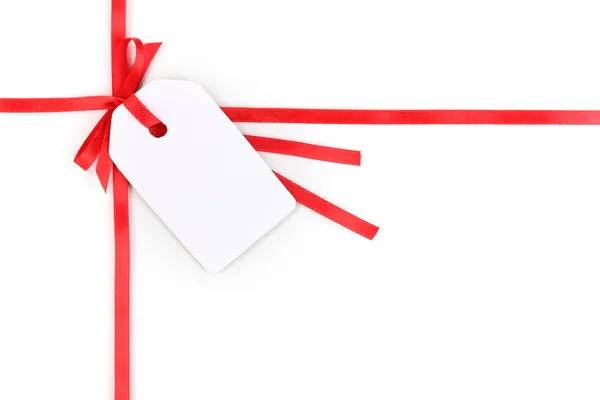Etiqueta regalo en blanco con lazo en cinta de satén rojo aislado en blanco —  Fotos de Stock