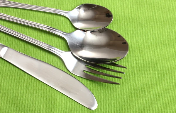Fork, spoon and knife on a green tablecloth — Stock Photo, Image