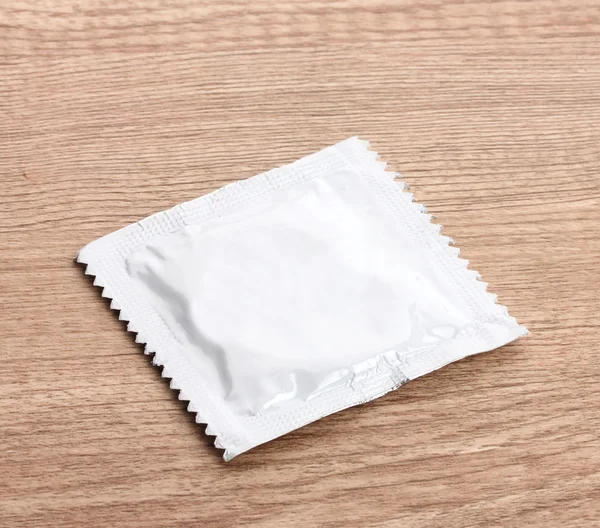Un preservativo su sfondo di legno — Foto Stock
