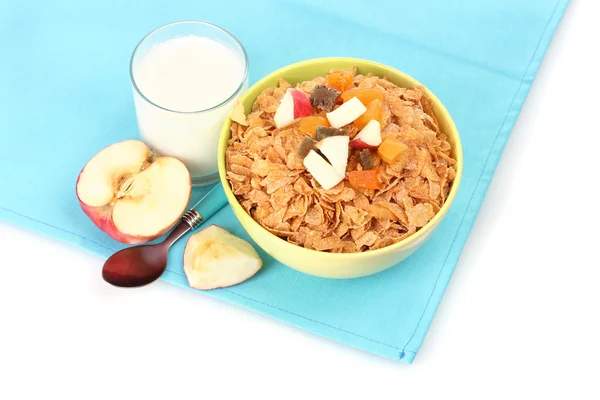 Smakelijke cornflakes in kom met gedroogde vruchten, glas van melk en apple op blauwe servet — Stockfoto