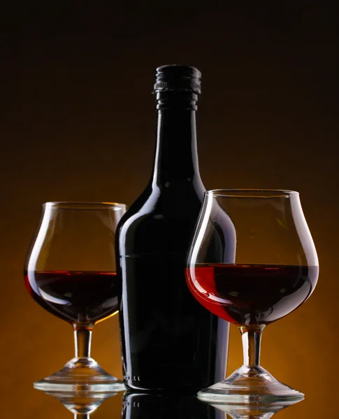Стаканы бренди и бутылки на коричневом фоне — стоковое фото