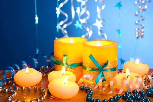 Hermosas velas, regalos y decoración en mesa de madera sobre fondo azul — Foto de Stock